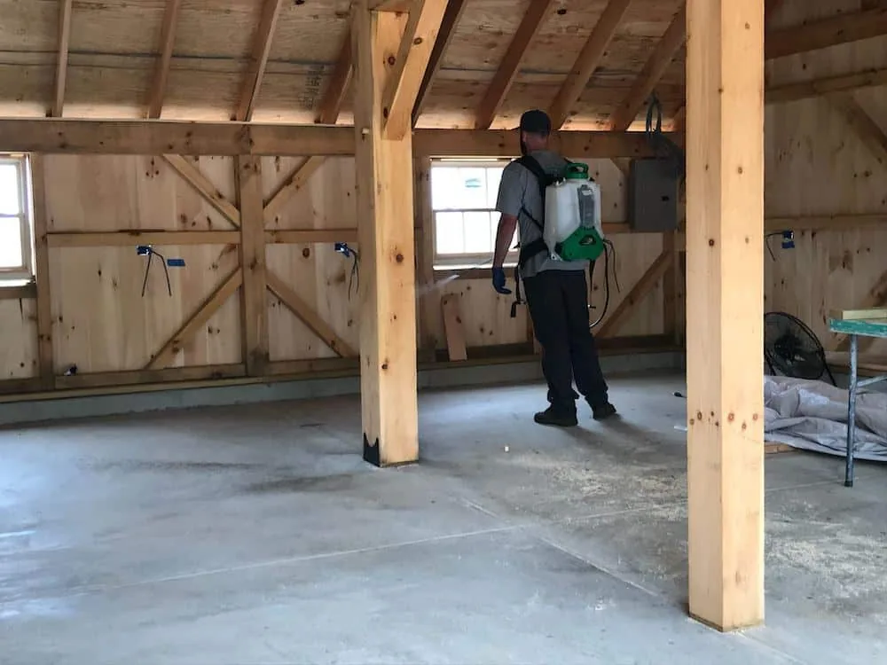 Pest Proof technician applying a perimeter treatment along a home foundation