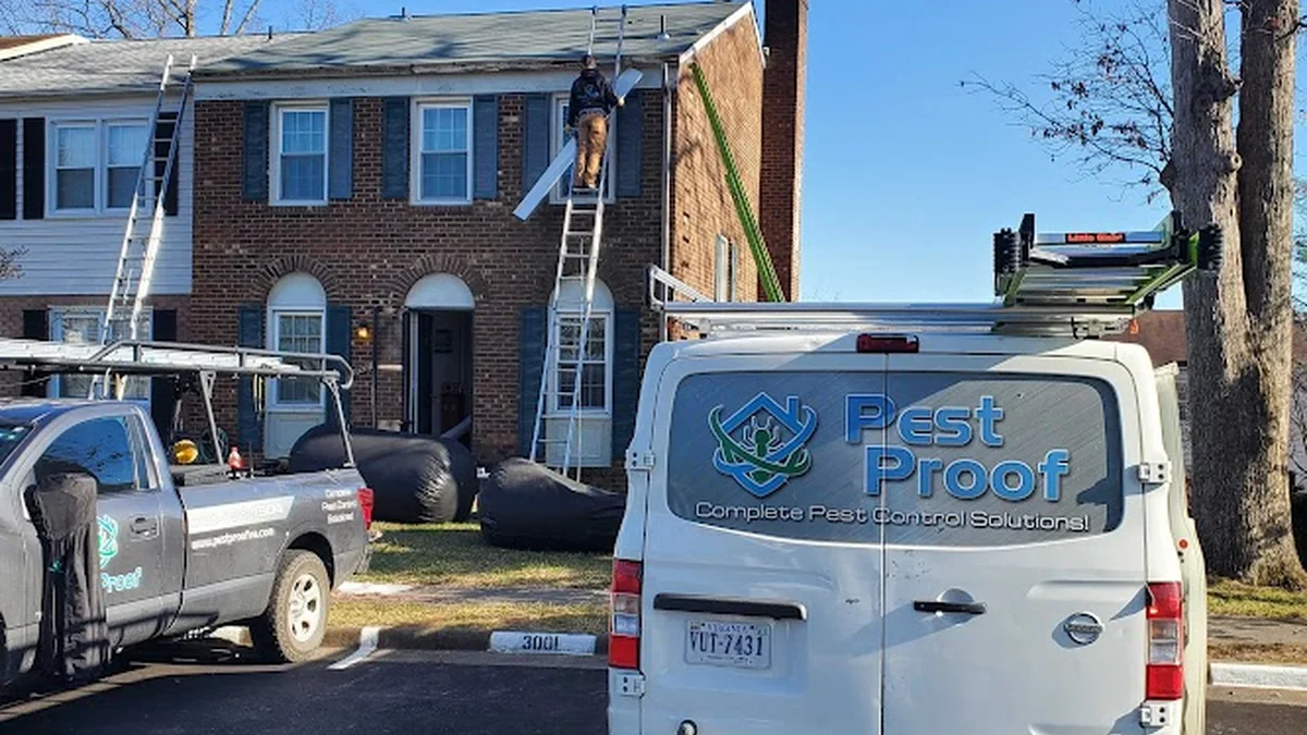 Technician installing exclusion mesh over a roof soffit and vent